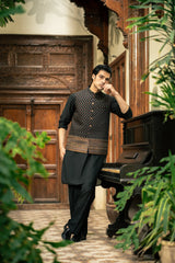 Man in traditional attire standing next to a piano in an elegant indoor setting with plants.