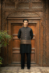 Man in traditional attire standing in front of an intricately carved wooden door.