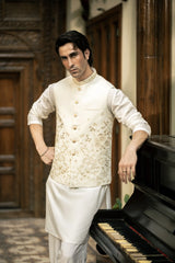 Man in traditional attire standing next to a piano in an ornate room.