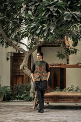 Man standing in a garden with a tree and traditional wooden bench in the background
