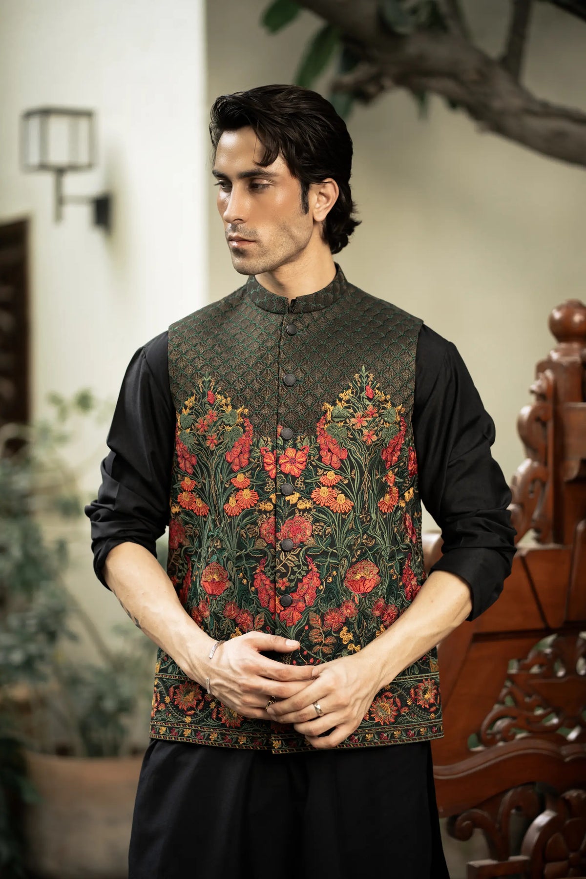 Man wearing a traditional embroidered vest over a black shirt in an indoor setting.