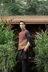 Person wearing a patterned vest over a black shirt in a garden setting