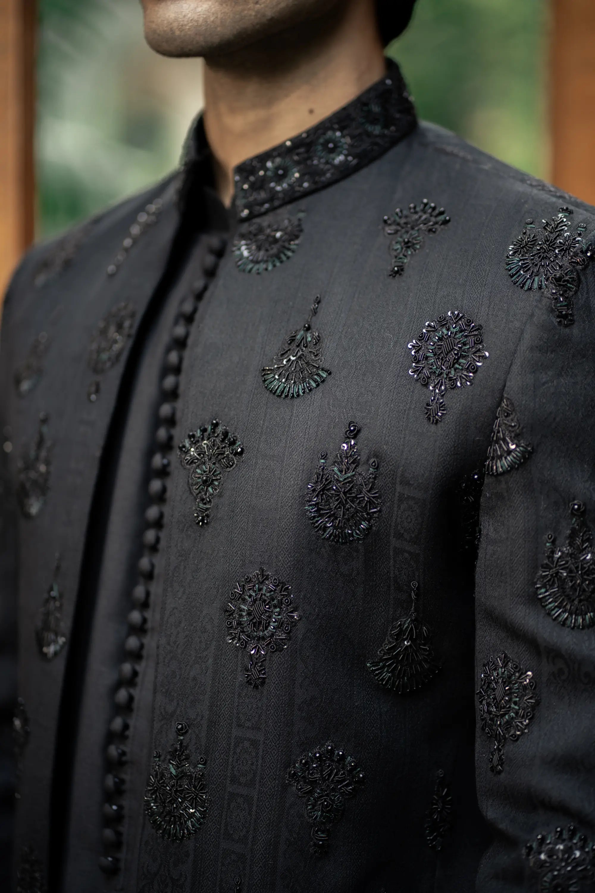 Black embroidered traditional outfit with intricate patterns on a blurred background
