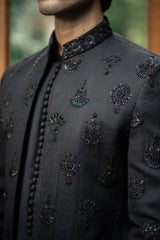 Black embroidered traditional outfit with intricate patterns on a blurred background