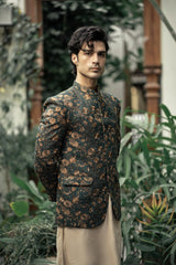 Man wearing a patterned jacket standing among green plants