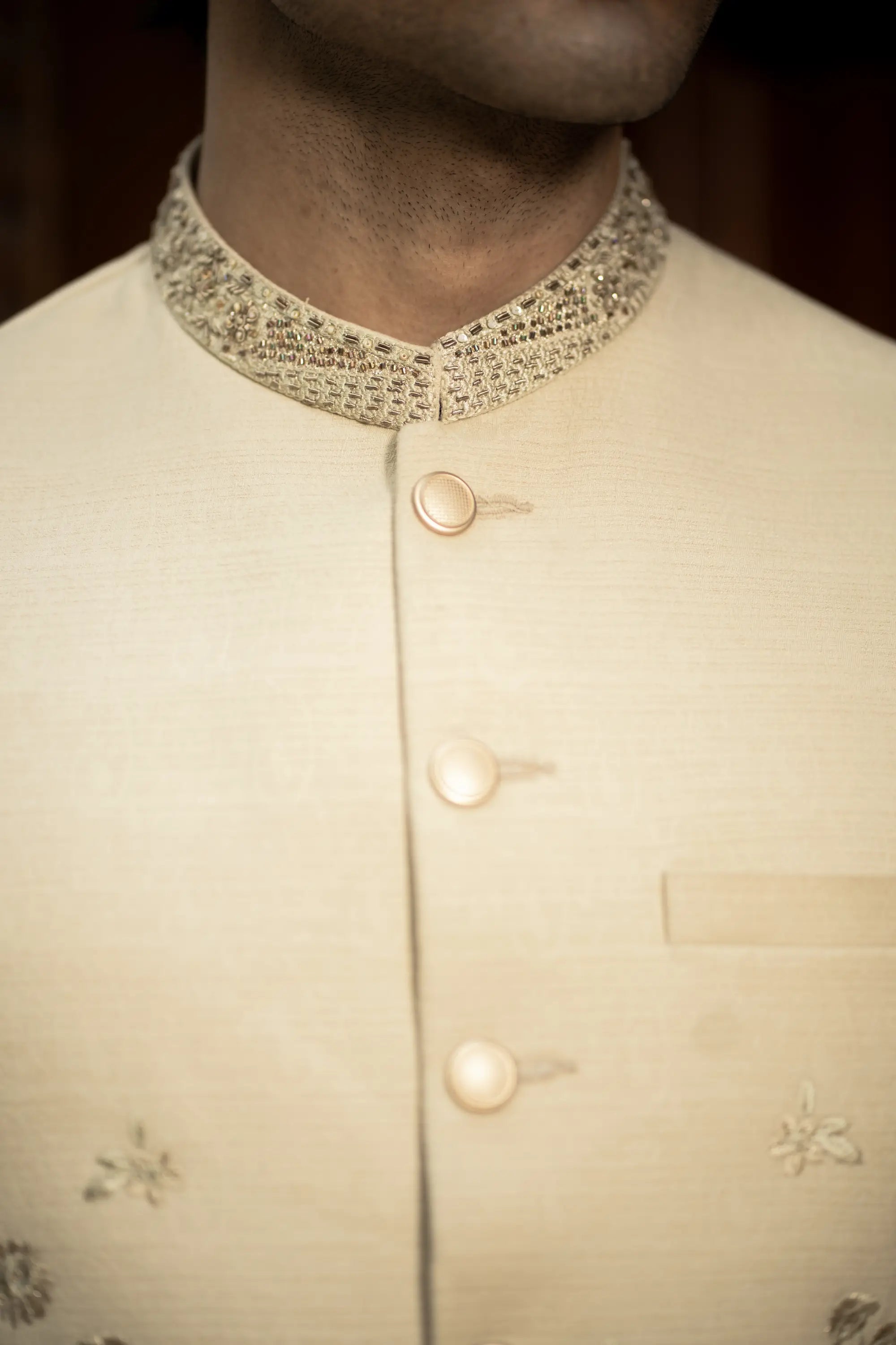 Close-up of a beige traditional outfit with intricate details on a dark background