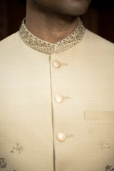 Close-up of a beige traditional outfit with intricate details on a dark background